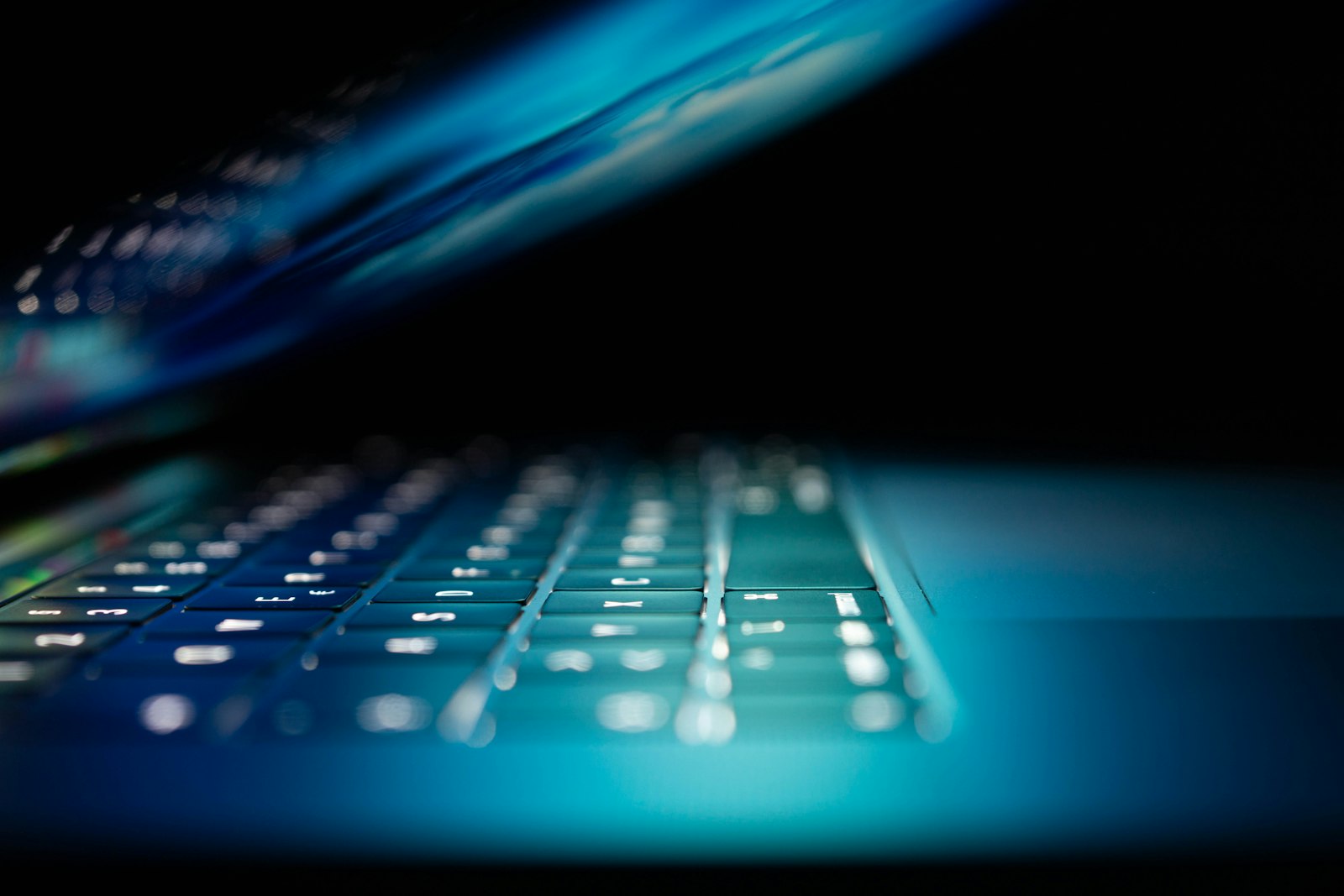 Half-closed laptop glowing blue in a dark room