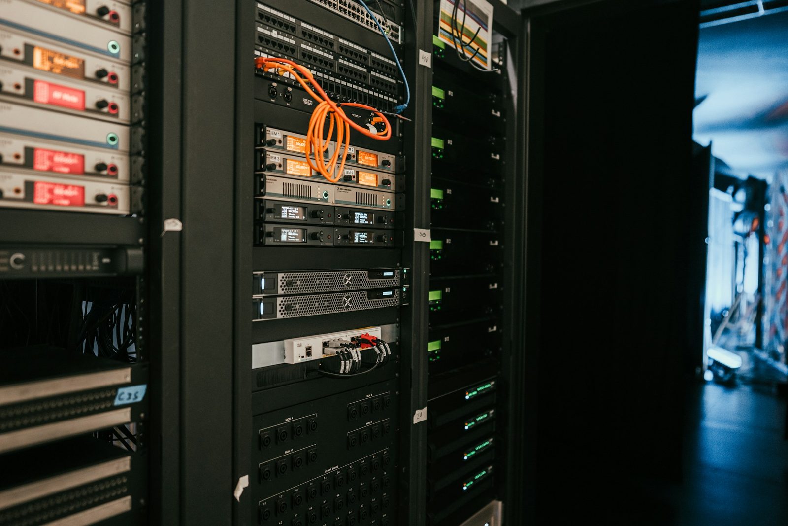 A dark server rack with patch cables and glowing status lights